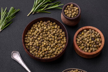Spice, allspice green in a wooden bowl on a black concrete background