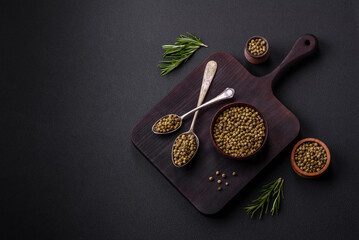 Spice, allspice green in a wooden bowl on a black concrete background