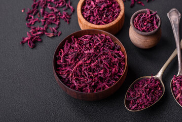 Dried beets in small slices in a wooden bowl on a black concrete background