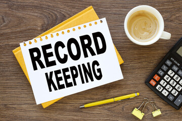 record keeping text on a white paper card, in black letters. lens on a wooden background. business...