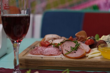 Serving sliced ​​meat and cheese on a large wooden platter with honey. Snack for wine and beer....