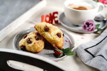 Valentines day breakfast  setting  - scones cappuccino heart and roses  on a tray, selective focus