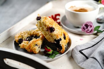 Valentines day breakfast  setting  - scones cappuccino heart and roses  on a tray, selective focus