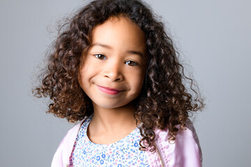 Adorable black little girl with beautiful curly hairstyle isolated over grey