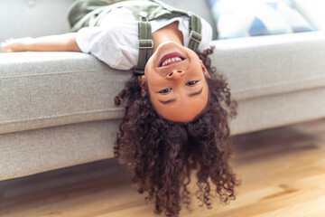 Little girl kid with very long beautiful hair upside down on sofa.