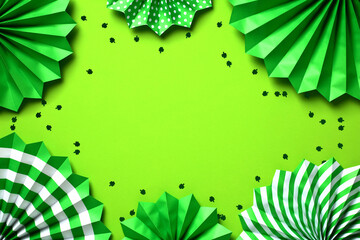 Frame of green paper fans and shamrock confetti on green background. Happy St. Patricks Day concept.
