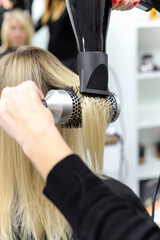 Naklejka premium hairdresser dries hair with a hairdryer to a woman after a haircut in the salon