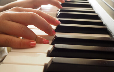 Obraz premium Hands playing piano. Pink nail polish fingers playing keyboard. Music lessons for kids.
