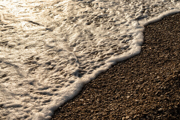 Waves splashing sand beach of Brac island, Croatia during beautiful summer sunset creating white foam