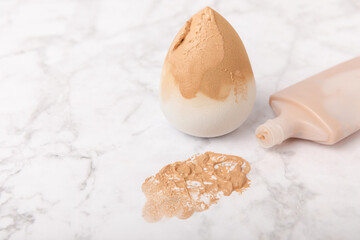 Makeup artist tools on marble texture table. Beauty blender, sponge, concealer and foundation. Beauty concept. Place for text.Copy space.