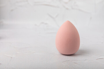 Beauty blender on light marble background. Cosmetics, makeup application tool. Beauty concept. Copy space. Place for text.