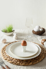 Fototapeta na wymiar Easter festive dinner with organic egg and decorative nest on linen tablecloth. Vertical format. Close up.