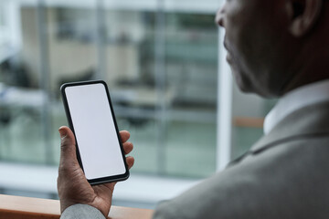 Close-up of hand of mature businessman holding smartphone with blank screen with copyspace for your text of announcement or advert