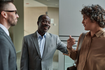 Happy mature African American boss or director of business company lauding one of subordinates during conversation at meeting
