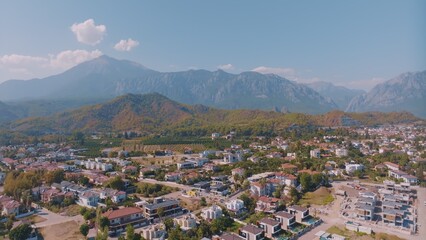 Fototapeta na wymiar Aerial panorama of small resort town. Hotels, houses and roads. Green hills around. Mountain landscape. Photography