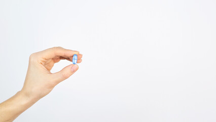 Fototapeta premium Blue medical pill in human hand. Medicine treatment of diseases, viruses, antibacterial therapy, White background isolated Space for text