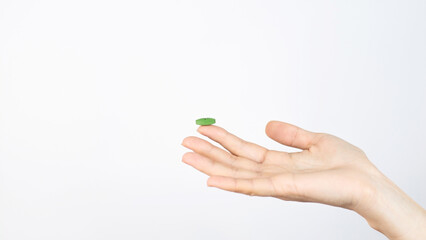 Green capsule lies on the finger isolated on white background Medical Pharmacy Treatment Health