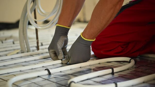HVAC Worker Installing Residential Radiant Floor Heating Plastic Pipeline. 