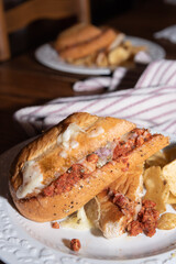 Italian sausage hoagie sandwich with chips on a table.