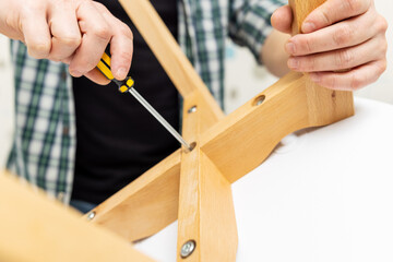 Fototapeta na wymiar Self-assembly furniture concept. The young man himself assembling chairs