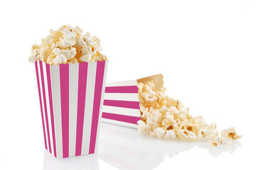 Two pink white striped carton buckets with tasty cheese popcorn, isolated on white background. Box with scattering of popcorn grains. Movies, cinema and entertainment concept.