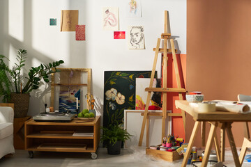 Part of studio of creative person with variety of items and equipment necssary for work, sketches on wall and small record player