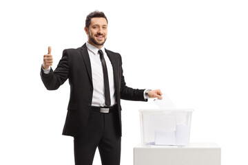 Smiling businessman casting a vote in a ballot box and showing thumbs up