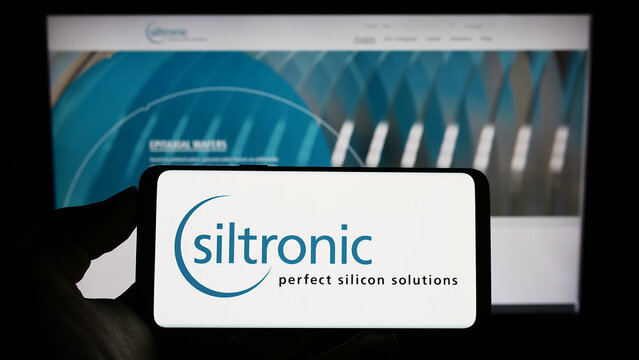 Stuttgart, Germany - 01-24-2023: Person holding cellphone with logo of German electronics company Siltronic AG on screen in front of business webpage. Focus on phone display.