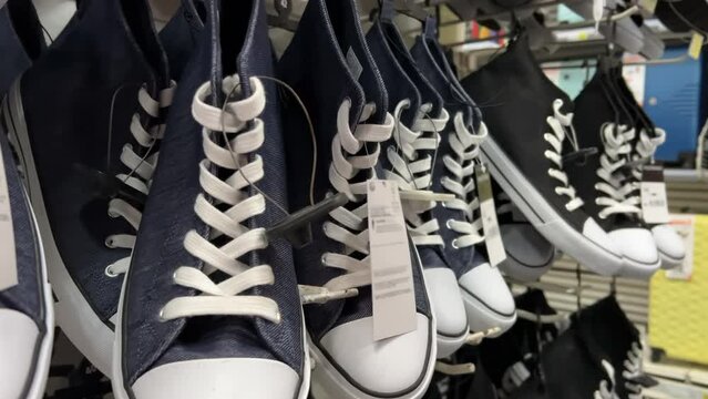 New canvas sneakers are hanging on the rack a shoe store. Closeup