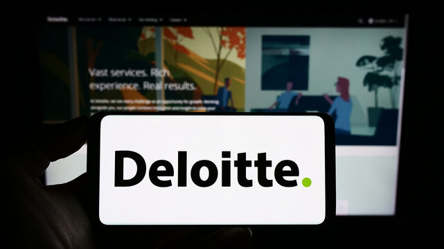 Stuttgart, Germany - 01-24-2023: Person holding cellphone with logo of professional services company Deloitte on screen in front of business webpage. Focus on phone display.