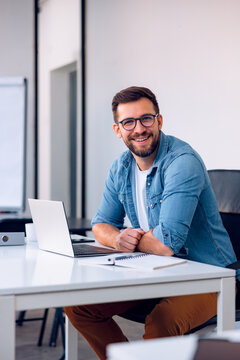 Portrait of attractive smiling man sitting in office and looking at camera.