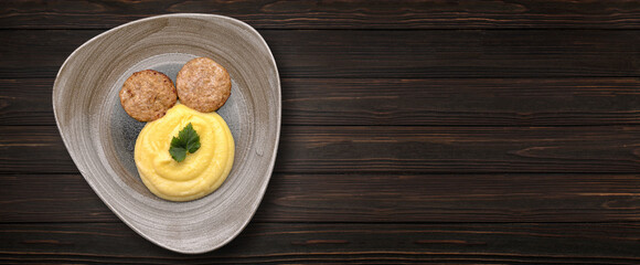Mashed potatoes with cutlets on a plate, on a wooden background