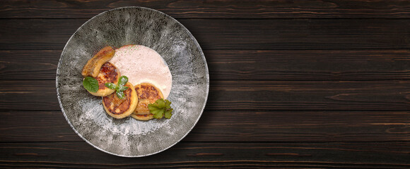 Curd cheesecakes with sauce, on a wooden background