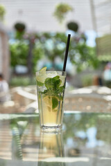 Summer mint refreshing mojito cocktail with ice in a glass outdoors in a cafe.