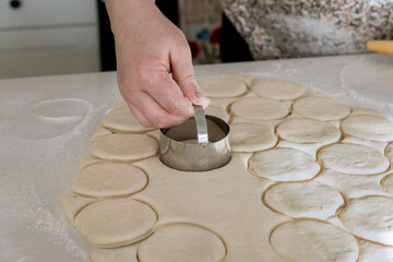 Donut dough is prepared from raw dough is cut into round pieces with rolling pin on baking table in bake