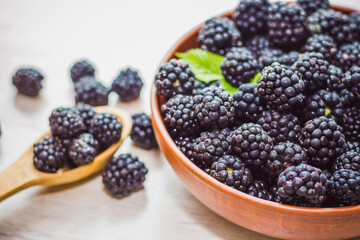 The blueberries in a wooden bowl and spoon and scattered on old wooden background closeup. Blackberry crop. Fresh berries, healthy lifestyle. 