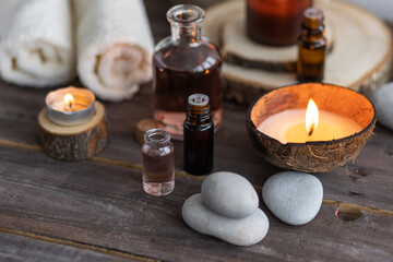 Fototapeta na wymiar Concept of natural essential organic oils, Bali spa, beauty treatment, relax time. Atmosphere of relaxation, pleasure. Candles, towels, dark wooden background. Alternative oriental medicine
