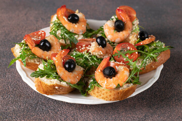 Bruschetta with shrimps, arugula, cream cheese and cherry tomatoes on a brown background, closeup