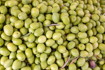Green fresh olives in a plastic box for sale in the market