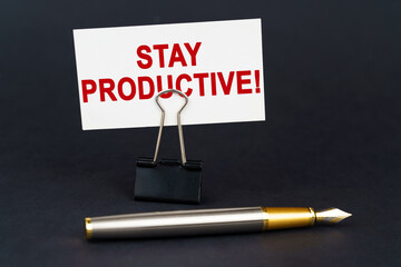 On the black surface is a pen, an office paper clip with a business card on which is written - Stay...
