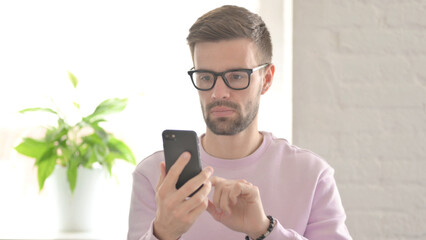 Young Man Browsing Internet on Smartphone