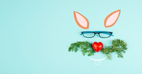 Easter rabbit face with a heart shaped nose, whiskers from carrot leaves and eyeglasse, holiday...