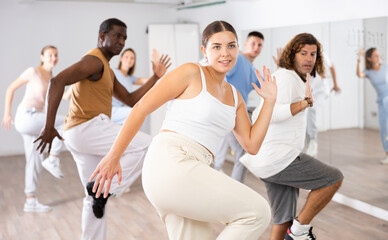 Group of energetic different people learning dance at dance class