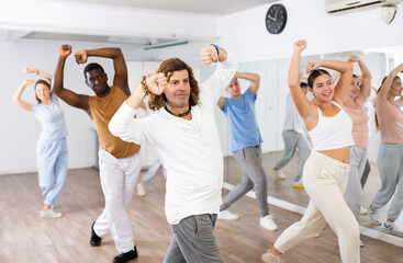 Group of smiling people of different ages dancing and practicing new movements in class. Sport, dance and urban culture concept