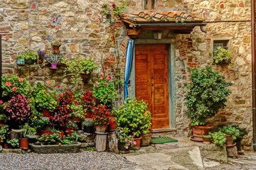 Fototapeta na wymiar Beautiful entrance to home in Montefiroalle, Italy, with red door and flowers