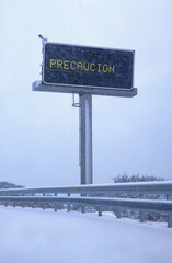 Fototapeta na wymiar Sign on a highway under a heavy snowfall showing the legend caution