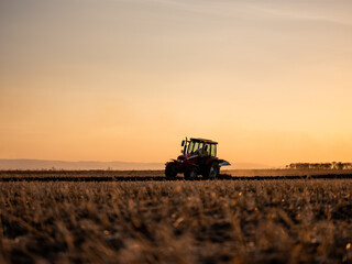 Tractor plowing and preparing stubble field for crop cultivation