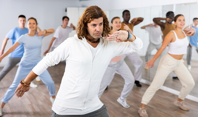Group of multinational happy adult people enjoying active dance movement in modern studio