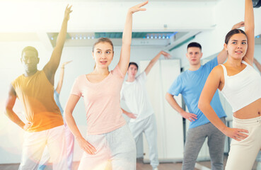 Nice men and women dancing synchronous group choreography in dance hall