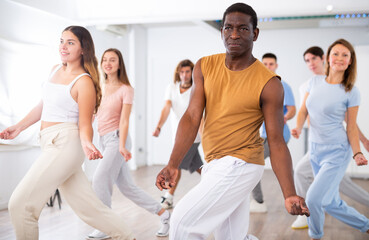 Group of sportive young adult diverse dancers performing dynamic movements during aerobic dance...